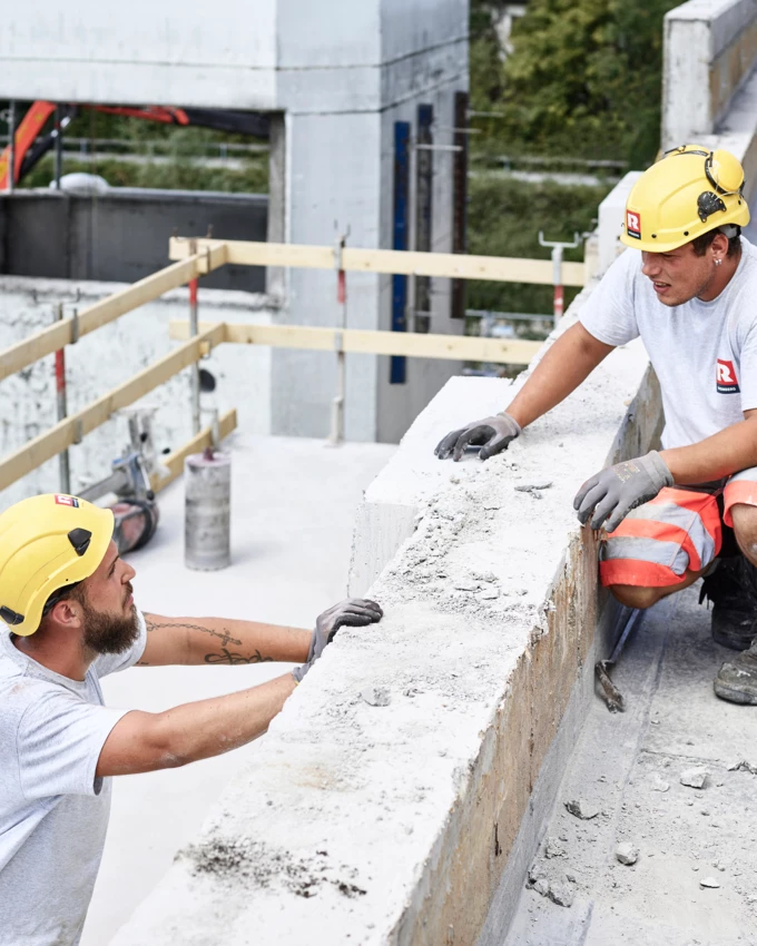 Angebot Mitarbeiter Rhomberg Bau Bauarbeiter, die sich auf Baustelle unterhalten