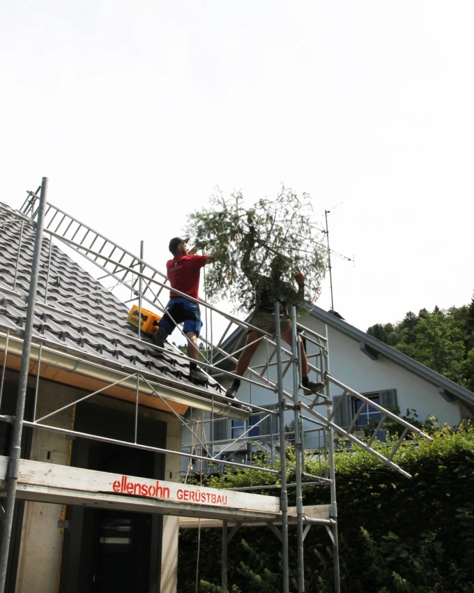 Handwerker beim Aufziehen des Firstbaumes auf den Rohbau der Wohnanlage im Dornbirner Eulental.